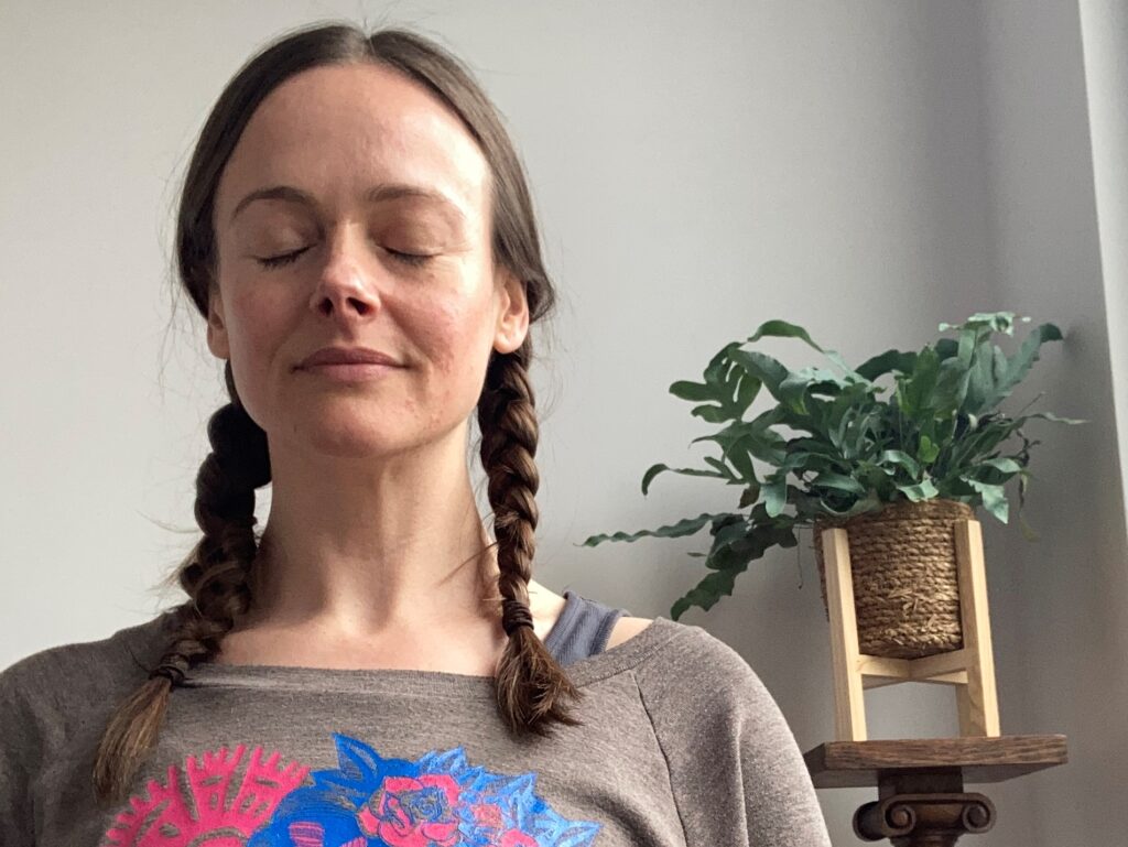 Image of woman in yoga studio with eyes closed in meditation, as a practice towards cultivating positive thought